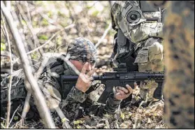  ??  ?? John DeMaria uses hand signals to indicate the number of “enemies” spotted in the woods of Jackson during training exercises with the militia Georgia Security Force. Members are ready for any crisis that spawns unrest on American soil.