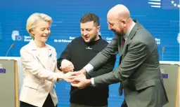  ?? OLIVIER MATTHYS/AP ?? European Commission President Ursula von der Leyen, left, Ukraine’s President Volodymyr Zelenskyy and European Council President Charles Michel join hands Thursday during an EU summit in Brussels as Zelenskyy wrapped up a rare trip outside Ukraine.