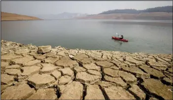  ?? ETHAN SWOPE/AP PHOTO ?? A kayaker fishes in Lake Oroville as water levels remain low due to continuing drought conditions in Oroville, Calif. A severe drought prompted California Gov. Gavin Newsom to ask the state’s nearly 40 million residents to voluntaril­y reduce their water use by 15% this year.