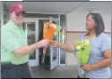  ??  ?? Country Florist’s driver Adam Weschler presents flowers to Bowie resident Monica Coggins at the Wawa in White Plains on Oct. 19, in honor of National Petal it Forward Day.