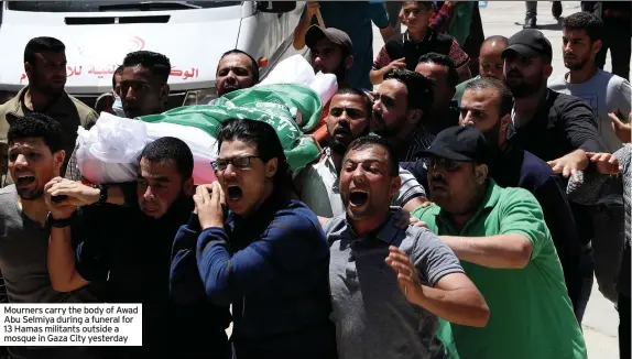  ??  ?? Mourners carry the body of Awad Abu Selmiya during a funeral for 13 Hamas militants outside a mosque in Gaza City yesterday