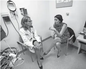  ??  ?? Melanie Thwing (right) talks with Elizabeth Gore, a radiation oncologist, before her exam. Every few months, Thwing makes the long drive from Waterloo, Iowa, where she works as a public defender, to Froedtert Hospital in Wauwatosa to get a checkup in...