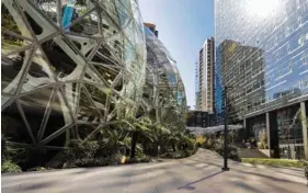  ?? AP PHOTO/ELAINE THOMPSON ?? In 2020, light reflects off the glass facade of a building on the Amazon campus outside the company headquarte­rs in Seattle.