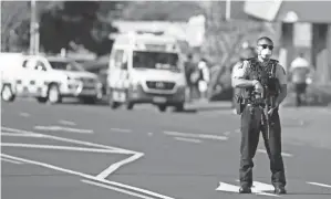  ?? ALEX BURTON/NEW ZEALAND HERALD VIA AP ?? A police officer stands outside a supermarke­t in Auckland, New Zealand, after a man who stabbed six people was fatally shot.