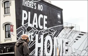  ?? ANDREW HARNIK/AP ?? A man walks by a “There’s No Place Like Home” mural in Washington, D.C., which President Trump wants reopened. The nation’s capital is easing its stay-at-home order this week.