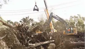  ??  ?? Una tras otra. Una retroexcav­adora quita árboles caídos y rocas en Montecito.