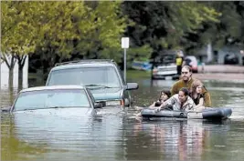  ?? ELIZABETH FLORES/AP ?? By wading and using an air mattress, residents inWaseca, Minn., get a closer look at submerged vehicles Thursday after heavy rains caused flooding in the upper Midwest.