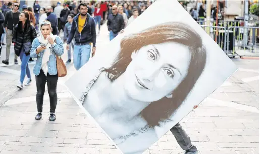  ?? PHOTO: YARA NARDI/REUTERS ?? In memory:
A protester carries a picture of Daphne Caruana Galizia during a rally outside the Courts of Justice in Valletta, Malta.