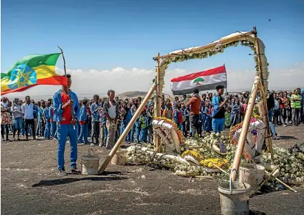  ?? AP ?? Primary school pupils stand next to floral tributes at the Ethiopian Airlines Boeing 737 Max 8 crash scene southeast of Addis Ababa yesterday, after walking an hour and a half from their school to pay their respects. Analysis of the jet’s flight recorders has begun in France.