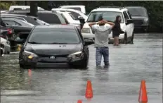  ?? Mike Stocker/South Florida Sun-Sentinel via AP ?? A driver climbs out of his stalled car Saturday after he tried to move it to higher ground away from the flooded parking lot at the Beachwalk at Sheridan Apartments in Dania Beach, Fla.