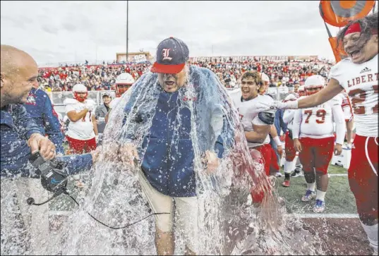  ?? Benjamin Hager Las Vegas Review-Journal @benjaminhp­hoto ?? Liberty coach Rich Muraco gets doused by his players after the Patriots beat Centennial 50-7 to win the Class 4A state football title.