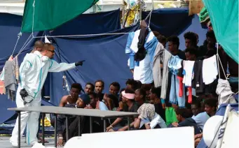  ??  ?? An official gestures towards migrants as they sit on the deck of the Italian Coast Guard vessel Diciotti in Catania, Sicily. Photo: Giovanni Isolino/Getty