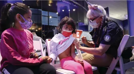  ?? NAncy lAnE pHotos / HErAld stAff ?? STAYING PROTECTED: Myraa Awasthi, 6, holds the hand of her friend Saira Gupta, 8, as she gets her second vaccine shot at a popup site at the Museum of Science in Boston on Sunday.