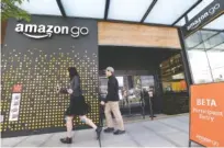  ?? FILE PHOTOS BY ELAINE THOMPSON/THE ASSOCIATED PRESS ?? People walk past an Amazon Go store in Seattle. The shops are convenienc­e stores that don’t use cashiers or checkout lines, but use a tracking system with sensors, algorithms and cameras to determine what a customer has bought.