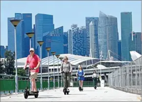  ?? ROSLAN RAHMAN/AFP ?? Visitors ride e-scooters along the Marina Bay in Singapore.