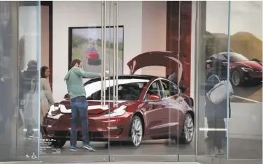  ?? Scott Olson / Getty Images ?? A Model 3 is inspected in a dealer showroom. Tesla fell short of its target of making 2,500 Model 3s a week.