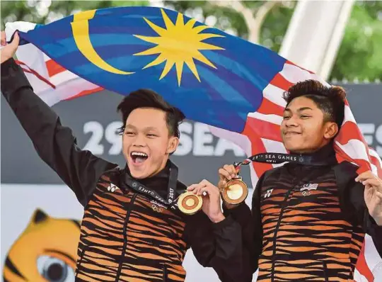  ??  ?? Hanis Nazirul (kanan) dan Jellson Jabillin memperaga pingat emas yang diraih pada hari terakhir, semalam.