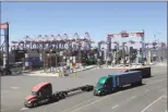  ?? Associated Press ?? Trucks travel along a loading dock at the Port of Long Beach in Long Beach, Calif.