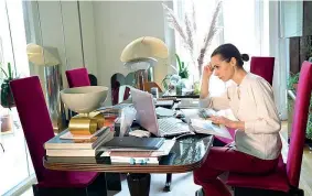  ??  ?? La designer Cristina Celestino, al lavoro sul suo tavolo da pranzo anni ‘40, ora diventato scrivania (foto Duilio Piaggesi/ Fotogramma)