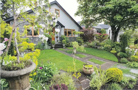  ??  ?? This home near Camosun College’s Lansdowne campus has a front entry path that mimics the driveway, where the owner took out paved rectangles and planted grass instead. Her front lawn is a circle bisected by the path. The front path features a cement pot on a plinth as a focal point.