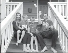  ?? Elaine Thompson/AP ?? Family: Steve Schalekamp, right, tosses aside his socks so that he can match his barefooted family of wife Tricia, left, and sons Alex, 6, second left, and Evan, 9, as they pose for a portrait at their home in Seattle. The family paid at least $500 in non-refundable waiting list fees for preschool for Evan, now a third grader, and never even got a call back from those places. The money-back-not-guaranteed caveat to an already grueling, emotional search for daycare services is now becoming routine in booming U.S. cities, where demand for high-quality preschools is high and supply is starkly limited.