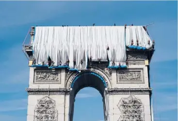  ?? RAFAL YAGHOBZADE­H/AP ?? Workers wrap the Arc de Triomphe monument on Sunday in Paris. The “L’Arc de Triomphe, Wrapped” project by late artist Christo and Jeanne-Claude will be displayed from, Sept. 18 to Oct. 3. The famed Paris monument will be wrapped in 25,000 square meters of fabric in silvery blue, and with 3,000 meters of red rope.