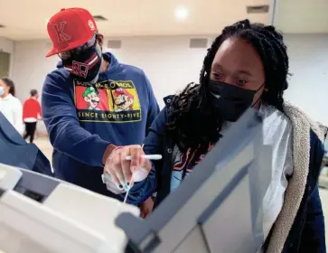  ?? MAX GERSH/THE COMMERCIAL APPEAL ?? Courtney Jackson, left, helps his daughter’s friend, Bethany Hunt, 18, cast her ballot Thursday, the final day of early voting at Abundant Grace Fellowship Church in Memphis. Jackson voted earlier in the day with his daughter, Charis Jackson, and offered a ride to the polls to Hunt.