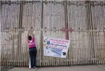  ??  ?? A woman hangs a banner at the US-Mexico border wall during a protest against the possibilit­y of deportatio­n of dreamers included in DACA program in Baja California, Mexico, on Monday. (AFP)