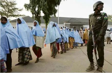  ?? Afolabi Sotunde/Reuters ?? Militar acompanha grupo de meninas que haviam sido sequestrad­as em Zamfara, na Nigéria