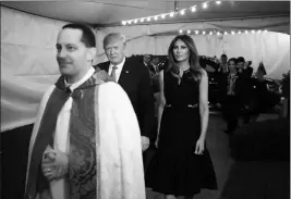  ?? ASSOCIATED PRESS ?? PRESIDENT DONALD TRUMP AND FIRST LADY MELANIA TRUMP are escorted from their motorcade vehicle by the Rev. James R. Harlan (left) as they arrive for Christmas Eve service at the Church of Bethesda-by-the-Sea in West Palm Beach, Fla., on Sunday.