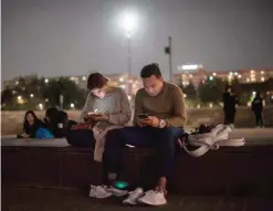  ??  ?? SEOUL: A couple looks at their mobile phones as they sit before the Han river in central in Seoul. Samsung Electronic­s slashed its latest quarterly profit estimate by one third in the wake of a highly damaging recall crisis that ended with the...