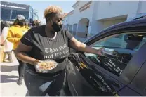  ?? JUSTIN SULLIVAN GETTY IMAGES ?? Volunteers pass out plates of food during a water distributi­on event Saturday in Houston, Texas.