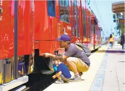  ??  ?? Jon Colon and his 2-year-old son, Jack, of City Heights take a closer look at the workings of a trolley car on Saturday.