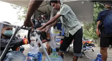  ??  ?? SEORANG penduduk mengambil bekalan air minum di kem perlindung­an sementara di taman Patulemo, Palu. - EPA
