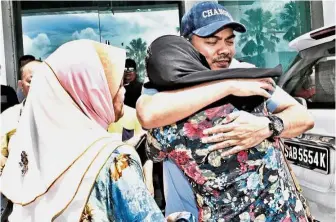  ??  ?? Tearful parting: Azis hugging his wife while a family member looks on before he is taken to the MACC office for questionin­g in Kota Kinabalu.