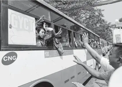  ?? Associated Press ?? Arrested protesters wave from a convoy of buses from Insein Prison to an undisclose­d location Wednesday in Yangon, Myanmar.