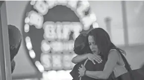  ??  ?? At a makeshift memorial on the Las Vegas Strip on Wednesday, Las Vegas resident Elisabeth Apcar, right, hugs a woman who was working at the concert venue when the Oct. 1 massacre happened.