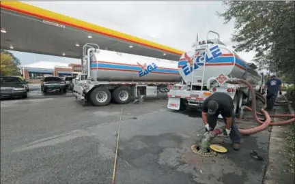  ?? CHUCK BURTON — THE ASSOCIATED PRESS FILE ?? People wait in line as Travis Hall, right, and Brandon Deese, back, pump fuel from two tanker trucks at a convenienc­e store in Wilmington, N.C. America’s rediscover­ed prowess in oil production is shaking up old notions about the impact of higher crude prices on the U.S. economy.