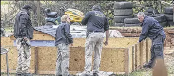  ??  ?? Clayton County police investigat­ors process the scene where the two girls were found sleeping near a doghouse and wooden pen in the 100 block of Flint River Road.