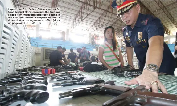 ?? JOY TORREJOS ?? Lapu-Lapu City Police Office director Sr. Supt. Lemuel Obon examines the firearms seized from the guards of a resort casino in the city after violence erupted yesterday dawn due to management conflict. (story on page 6)