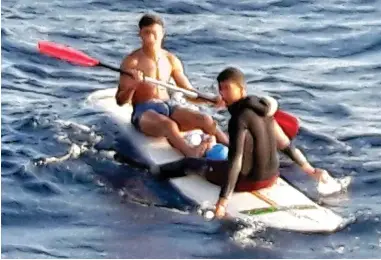  ??  ?? Adrift: The migrants, one in trunks, use a paddle board to cross from Morocco to Spain