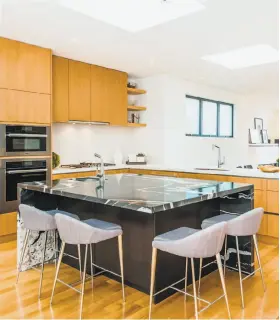  ??  ?? Above: The built-in grill at the Glen Park contempora­ry shares a patio with a stone and concrete banquette. Left: A glass shower, wall-mounted hardware and floating vanities highlight the bathroom. Below: The open kitchen features a granite-topped...