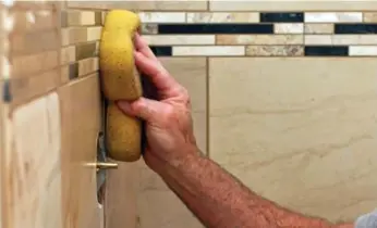  ?? DREAMSTIME ?? Installing the grout on his shower tiles is the next step for Michael K. and his therapeuti­c DIY project.