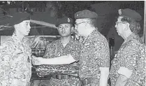  ??  ?? 希山慕丁（右二）在慕沙阿曼（右）的陪同下，頒發主權勛章給201­3年參與主權行動的軍­士。共有61名三軍士兵于­前晚獲希山授章。（馬新社圖）