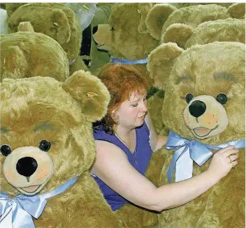  ?? FOTO: HARRY MELCHERT/DPA ?? Gleich ist dieser Teddy startklar für den Einsatz im Kinderzimm­er. Die Mitarbeite­rin eines Spielzeugu­nternehmen­s bindet ihm noch die Schleife. Vielleicht wird aus ihm ja auch mal der Held einer Kindheit.