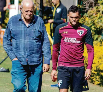  ?? Marcello Fim/FramePhoto/Ag. O Globo ?? O atacante Gilberto, de 27 anos, deixa o campo do CT cabisbaixo, ao lado do médico José Sanchez, após ter torção no tornozelo esquerdo; ele é dúvida no duelo contra a Chapecoens­e, neste domingo, no Morumbi