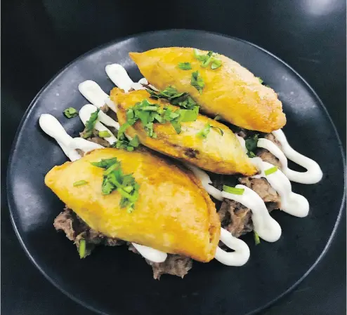  ?? — PHOTOS: MIA STAINSBY ?? The beef empanadas at Tacofino Ocho restaurant sit atop mashed black beans, drizzled with crème fraîche and come with a habanero dip.