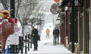  ?? ERIN WOODIEL — THE ARGUS LEADER VIA AP ?? Pedestrian­s stand as snow falls around them ahead of a winter storm on Tuesday, Feb. 21, 2023, in Sioux Falls, S.D. A wide swath of the Upper Midwest is bracing for a historic winter storm. The system is expected to bury parts of the region in 2feet of snow, create dangerous blizzard conditions and bring along bitter cold temperatur­es.