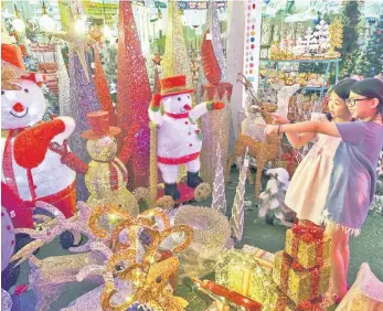  ??  ?? Kuan Xin Lee (right) together with her sister Kuan Si look at the beautiful Christmas season decoration­s at a shopping mall in Kuala Lumpur on Christmas Eve. — Bernama photo