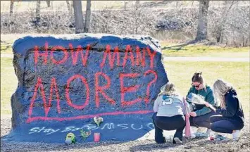  ?? Todd Mcinturf / The Detroit News / Tribune News Service ?? From left, Ella Huff, of Grand Rapids, Mich., joins fellow Michigan State University students Sophie Apple and her sister, Abbey Apple, both of Washington Township, Mich., as they place flowers at “The Rock” Tuesday morning.